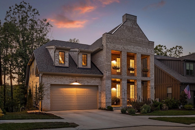 view of front facade featuring brick siding, a shingled roof, an attached garage, board and batten siding, and driveway
