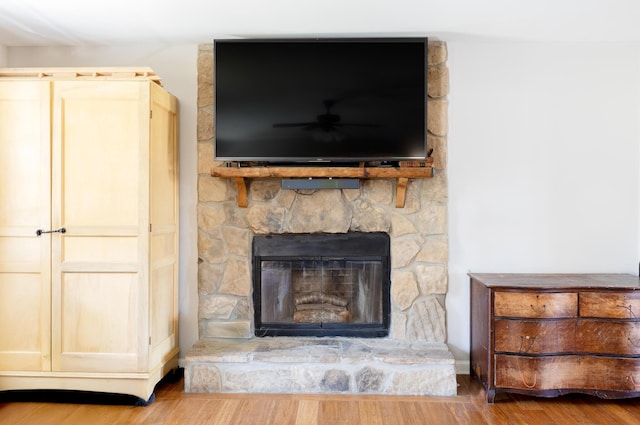 interior details featuring ceiling fan, a fireplace, and wood finished floors