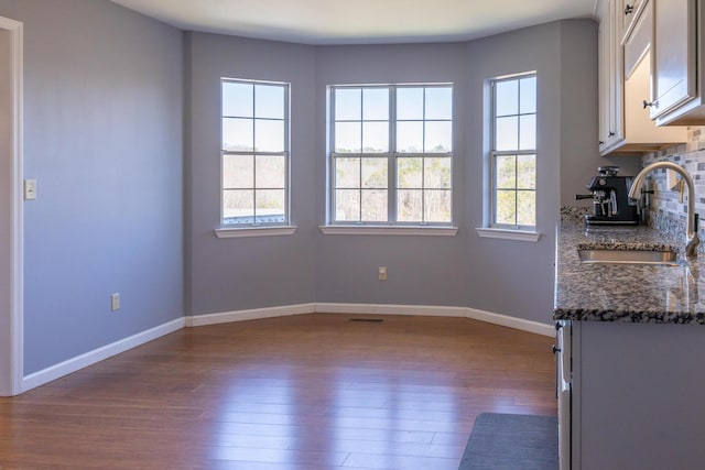 interior space with a healthy amount of sunlight, baseboards, dark wood finished floors, and a sink