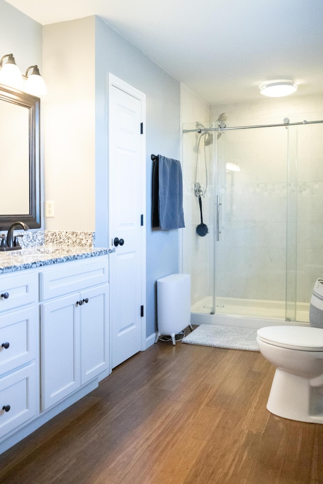 full bathroom featuring vanity, a shower stall, toilet, and wood finished floors