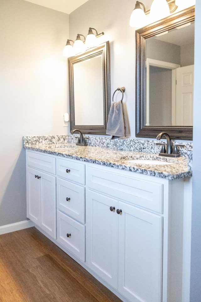 full bath with double vanity, a sink, and wood finished floors