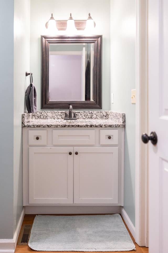 bathroom featuring visible vents, vanity, baseboards, and wood finished floors