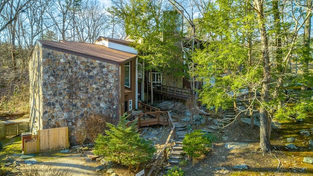 view of home's exterior with stone siding and fence