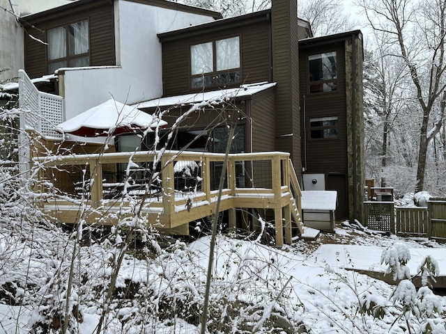 snow covered house featuring a wooden deck