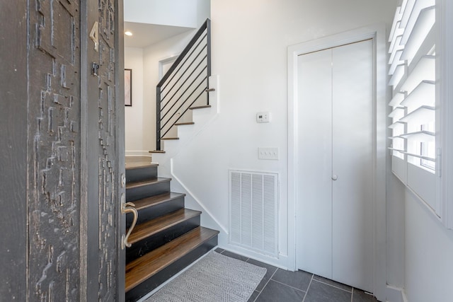 entrance foyer featuring stairway, visible vents, and dark tile patterned flooring