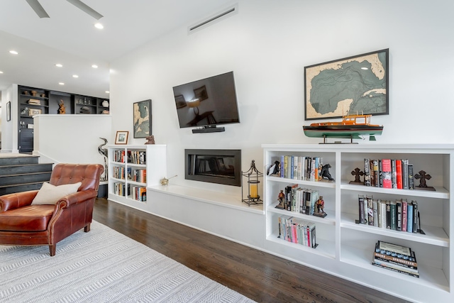 living area featuring a glass covered fireplace, visible vents, recessed lighting, and wood finished floors