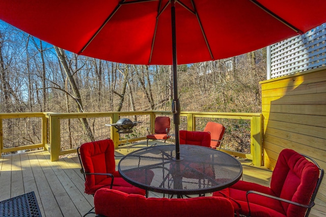 wooden deck with outdoor dining area and a view of trees