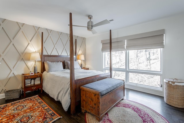 bedroom featuring an accent wall, dark wood finished floors, and a ceiling fan