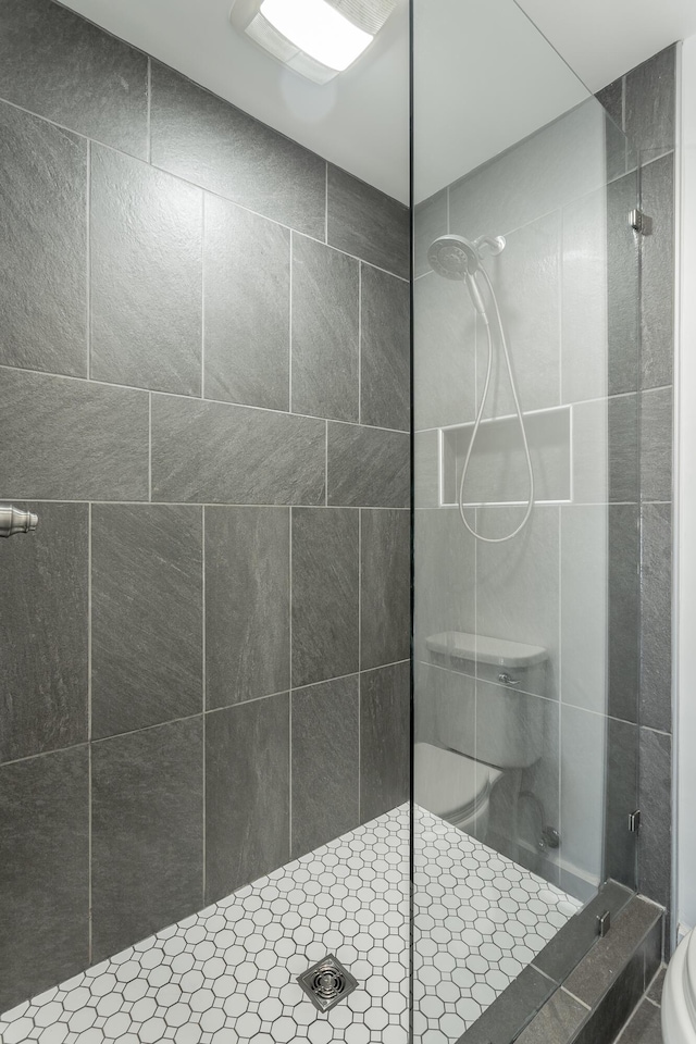 full bath with tiled shower and toilet