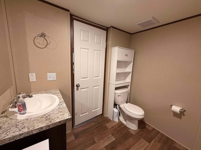 bathroom with crown molding, visible vents, toilet, vanity, and wood finished floors