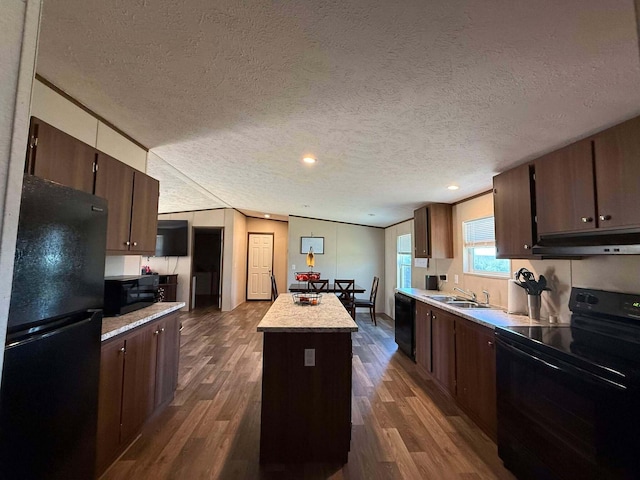 kitchen with dark wood-style floors, a center island, under cabinet range hood, black appliances, and a sink