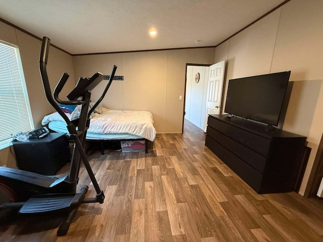 bedroom featuring a textured ceiling, ornamental molding, and wood finished floors