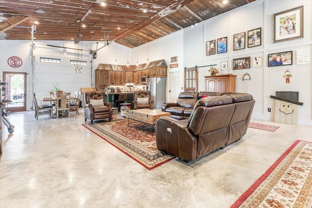 living area with concrete flooring, a towering ceiling, and a barn door