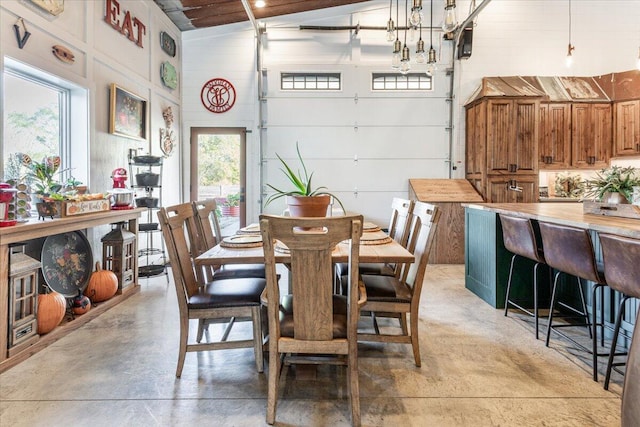 dining space with concrete flooring, a healthy amount of sunlight, and a high ceiling