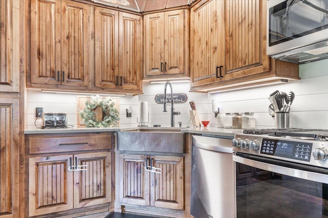 kitchen featuring brown cabinets, appliances with stainless steel finishes, a sink, and tasteful backsplash