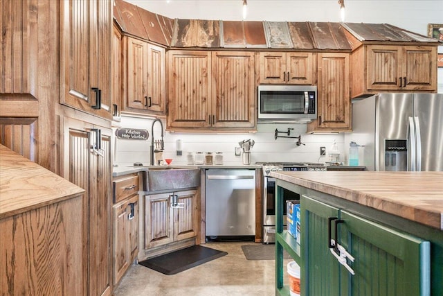 kitchen featuring concrete flooring, stainless steel appliances, butcher block countertops, a sink, and backsplash