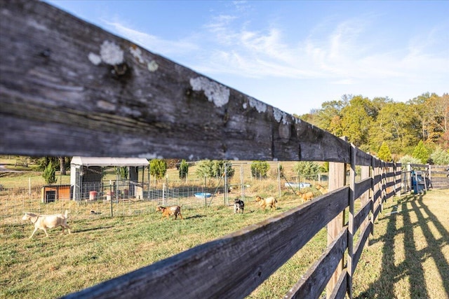 view of yard featuring an outbuilding, a rural view, and fence