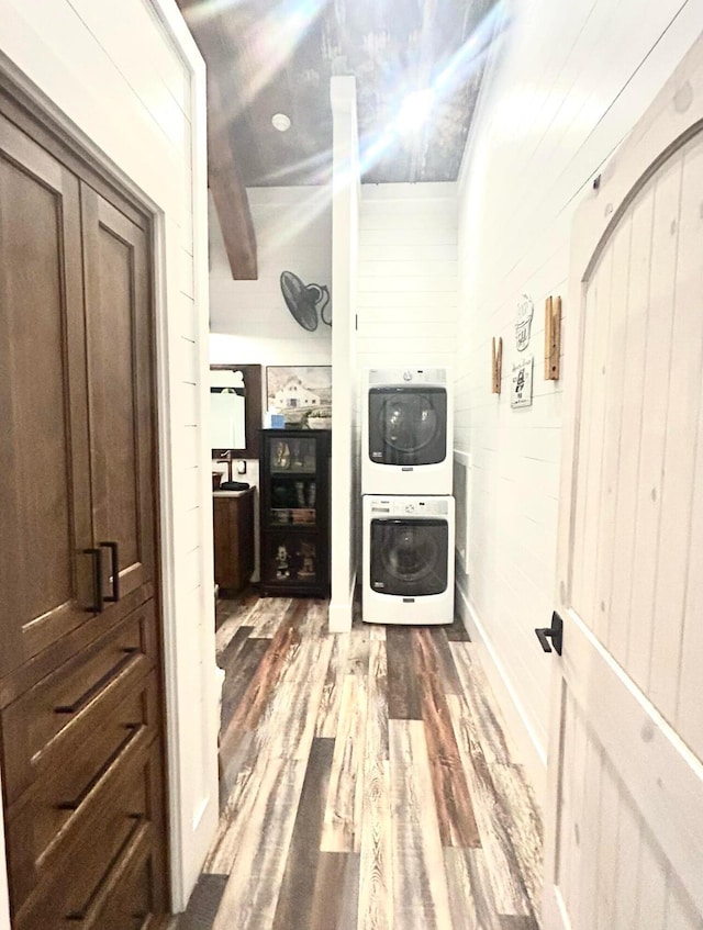 interior space with stacked washer / dryer, wood walls, and wood finished floors