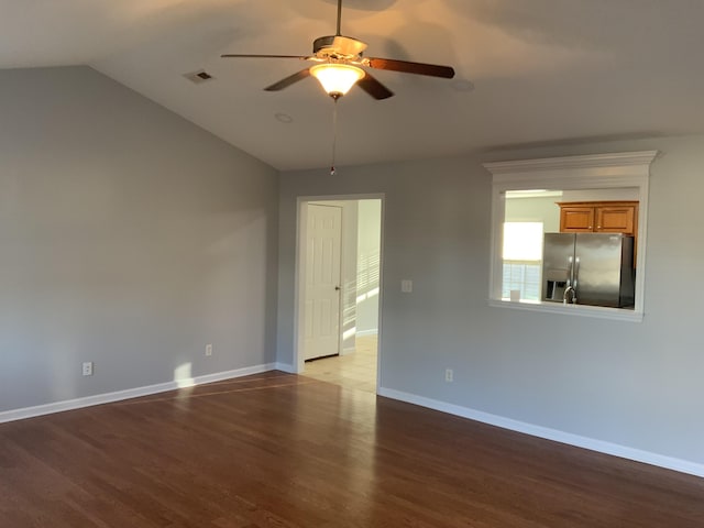 empty room featuring baseboards, visible vents, a ceiling fan, wood finished floors, and vaulted ceiling