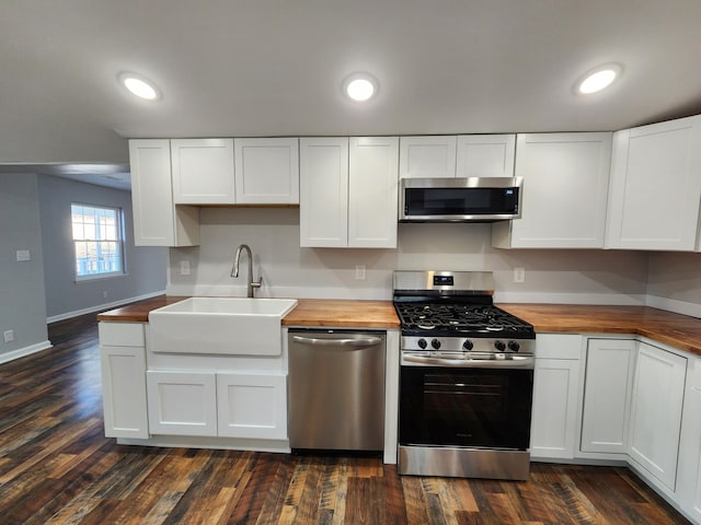 kitchen featuring butcher block countertops, appliances with stainless steel finishes, dark wood-type flooring, a sink, and recessed lighting