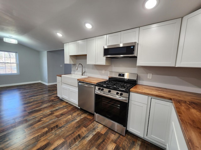 kitchen with stainless steel appliances, butcher block countertops, a sink, vaulted ceiling, and dark wood-style floors