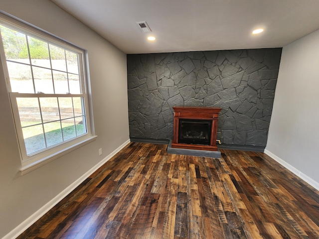 unfurnished living room with dark wood-type flooring, visible vents, a fireplace, and baseboards