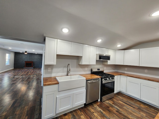 kitchen featuring stainless steel appliances, butcher block counters, dark wood-style flooring, and a sink