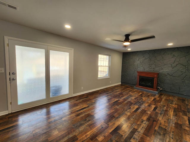 unfurnished living room featuring a fireplace, visible vents, dark wood-type flooring, ceiling fan, and baseboards