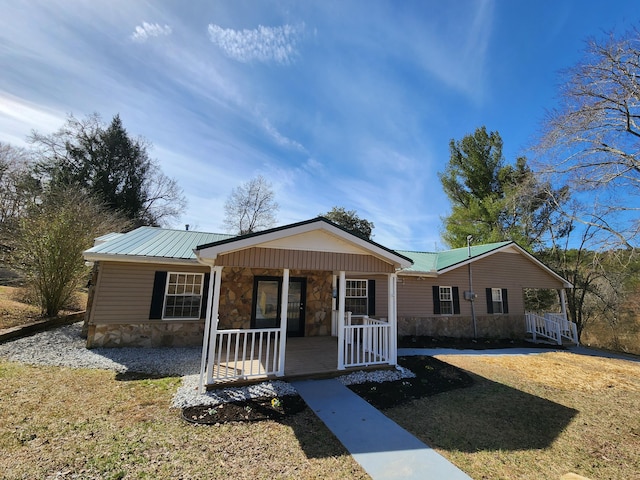 view of front facade with covered porch, stone siding, metal roof, and a front yard