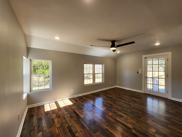 spare room featuring dark wood-style floors, vaulted ceiling, baseboards, and ceiling fan