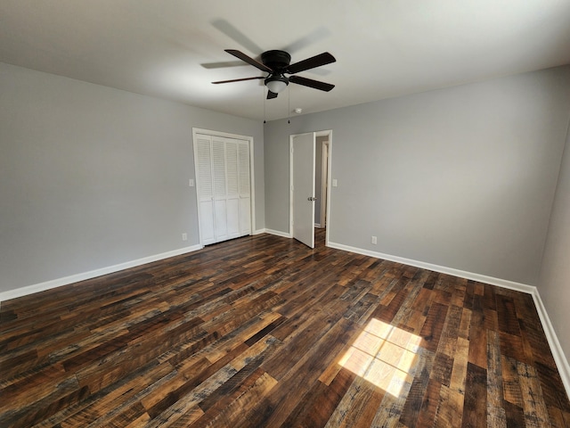 unfurnished bedroom featuring a ceiling fan, a closet, dark wood finished floors, and baseboards