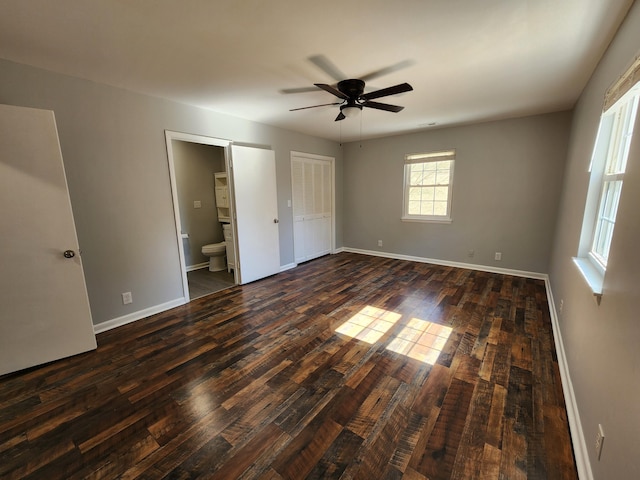 unfurnished bedroom with dark wood-style flooring, connected bathroom, baseboards, and ceiling fan