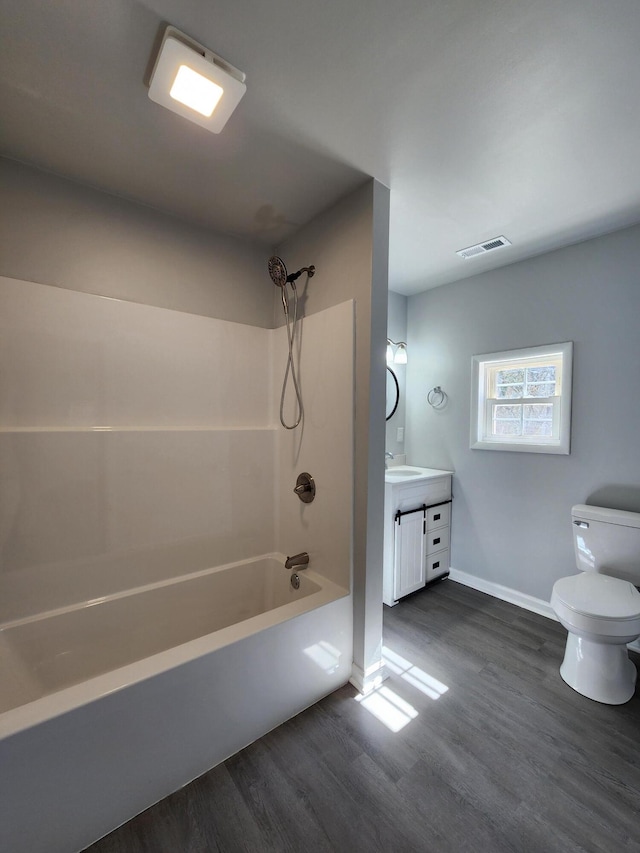 full bath with toilet, wood finished floors, vanity, visible vents, and washtub / shower combination