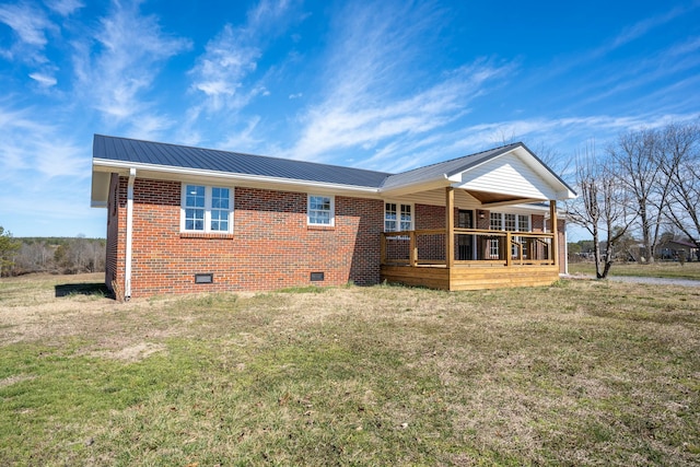 rear view of house featuring crawl space, a yard, metal roof, and brick siding