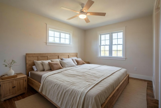 bedroom with dark wood-type flooring, multiple windows, a ceiling fan, and baseboards