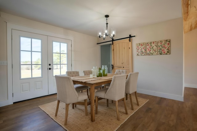 dining area with dark wood-type flooring, a chandelier, baseboards, and a barn door