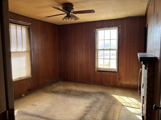 carpeted empty room featuring ceiling fan and wooden walls