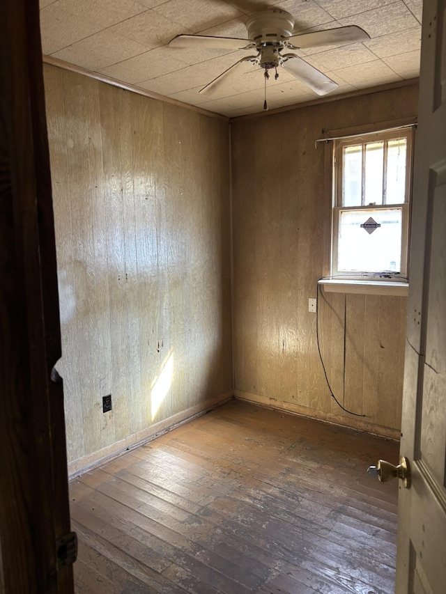 empty room with wood walls, hardwood / wood-style flooring, and a ceiling fan