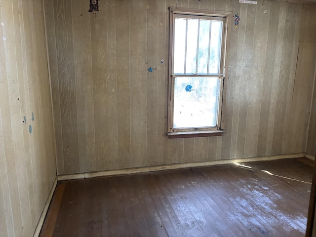 unfurnished room with wood walls and hardwood / wood-style floors