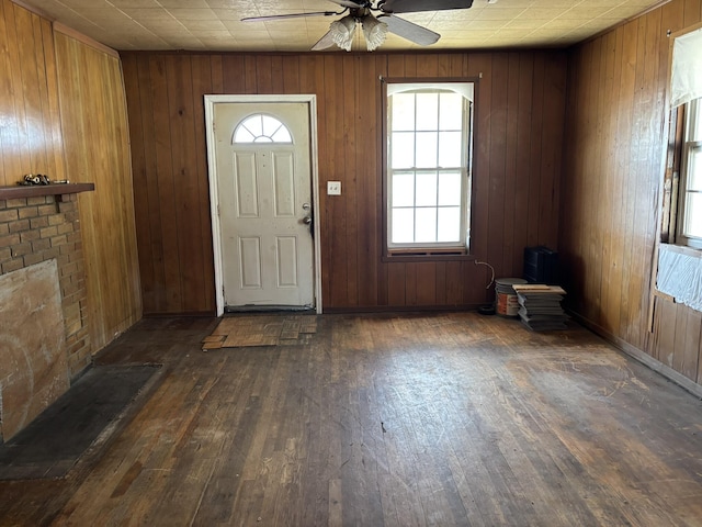 foyer with wood-type flooring, wooden walls, and ceiling fan