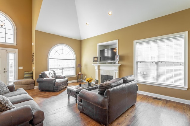 living area featuring visible vents, high vaulted ceiling, wood finished floors, and a fireplace