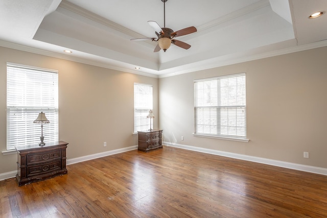 spare room with a tray ceiling, wood finished floors, and ceiling fan
