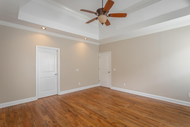 unfurnished room with baseboards, a tray ceiling, wood finished floors, and ceiling fan