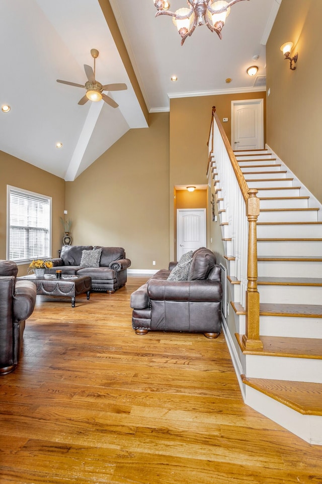 living room with baseboards, ornamental molding, stairway, wood finished floors, and ceiling fan with notable chandelier
