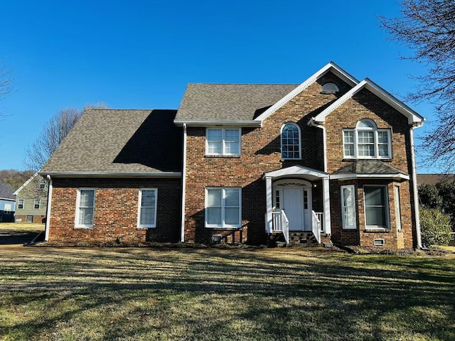 view of front of property featuring a front lawn, a shingled roof, and brick siding