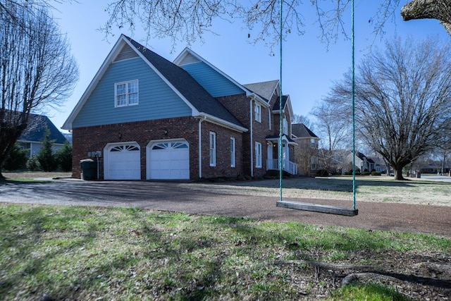 view of property exterior featuring brick siding, an attached garage, and aphalt driveway