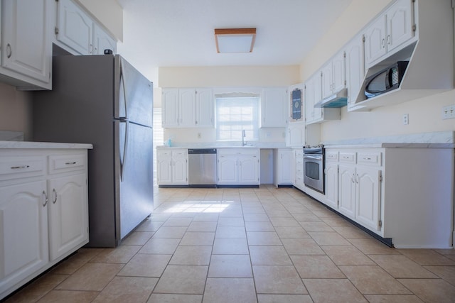 kitchen with light tile patterned floors, under cabinet range hood, stainless steel appliances, a sink, and light countertops