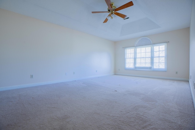 spare room featuring carpet, a raised ceiling, visible vents, and baseboards