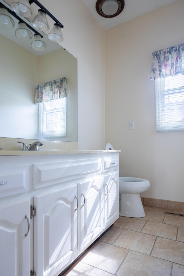 half bathroom featuring toilet, plenty of natural light, visible vents, and vanity