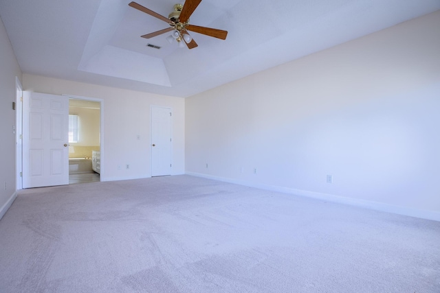 unfurnished bedroom featuring ensuite bath, carpet flooring, a raised ceiling, and baseboards